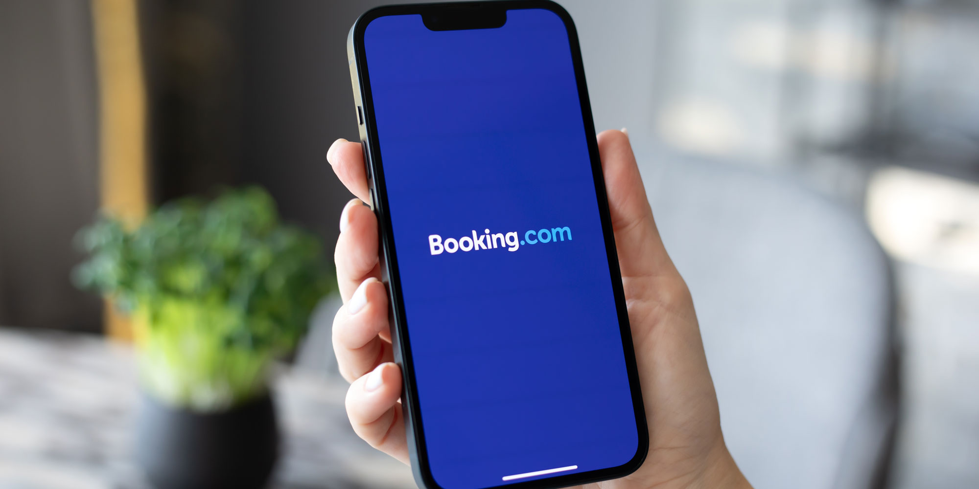 Hand holding a smartphone with the Booking.com logo on the screen